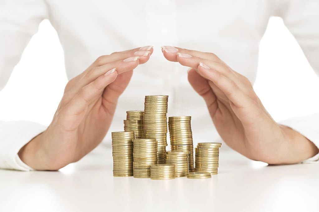 Female hands protecting stack of coins showing the importance of income protection insurance