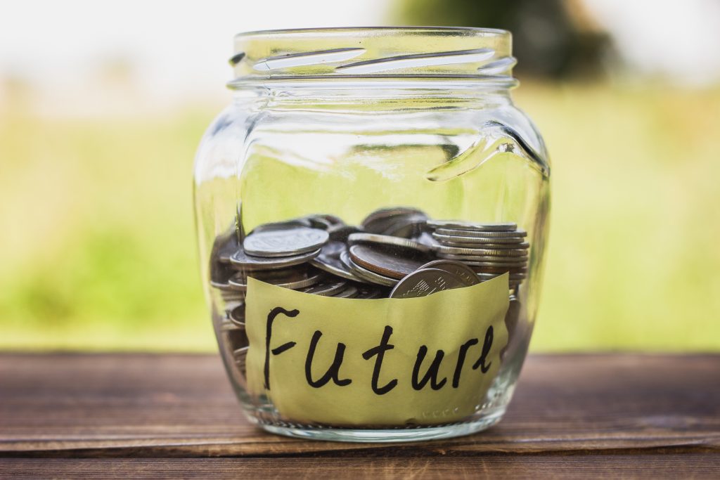 Glass jar half filled with coins indicating savings for future through self-managed super funds.